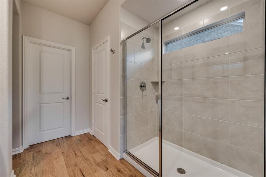 Master bathroom featuring a glass enclosed shower with door and hardwood flooring