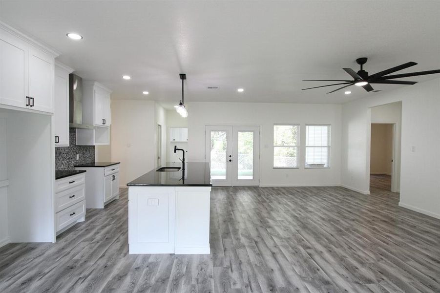 Kitchen featuring white cabinetry, wall chimney range hood, pendant lighting, light wood finished floors, and recessed lighting Kitchen featuring white cabinetry, wall chimney range hood, pendant lighting, light wood finished floors, and recessed lighting