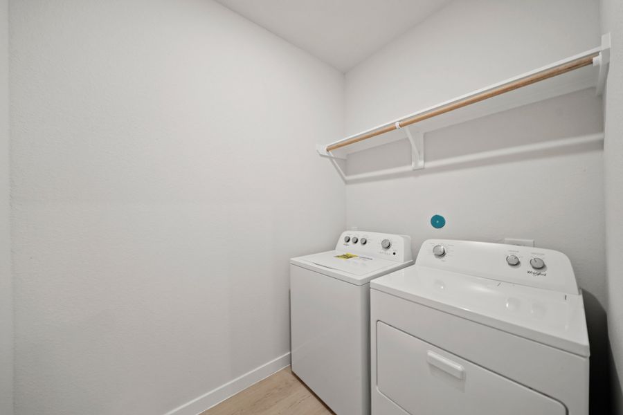 A white laundry room with a white shelf and a white wall.