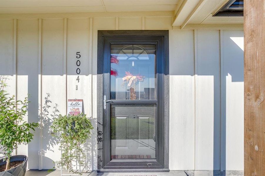 View of exterior entry featuring storm door and covered porch View of exterior entry featuring storm door and covered porch