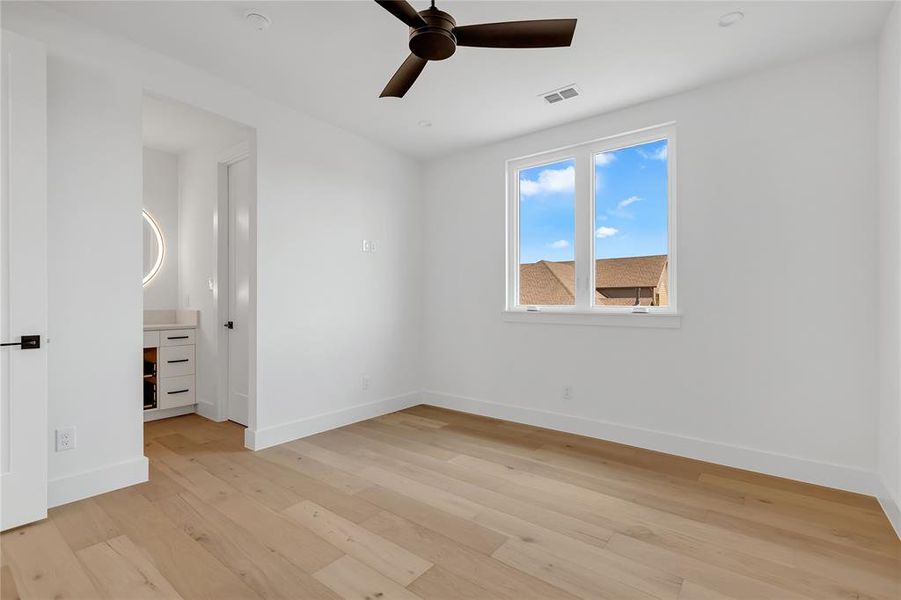 Empty room with a ceiling fan and light wood-type flooring Empty room with a ceiling fan and light wood-type flooring