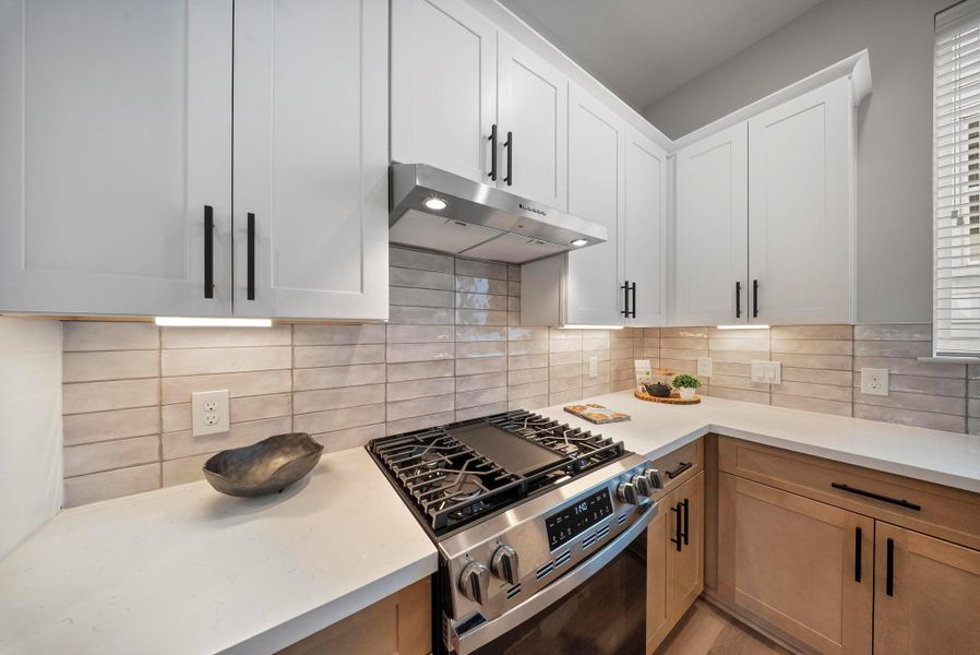 Modern kitchen with sleek cabinetry, stainless steel appliances, and under-cabinet lighting. Features a stylish tile backsplash and ample countertop space, perfect for cooking and entertaining.