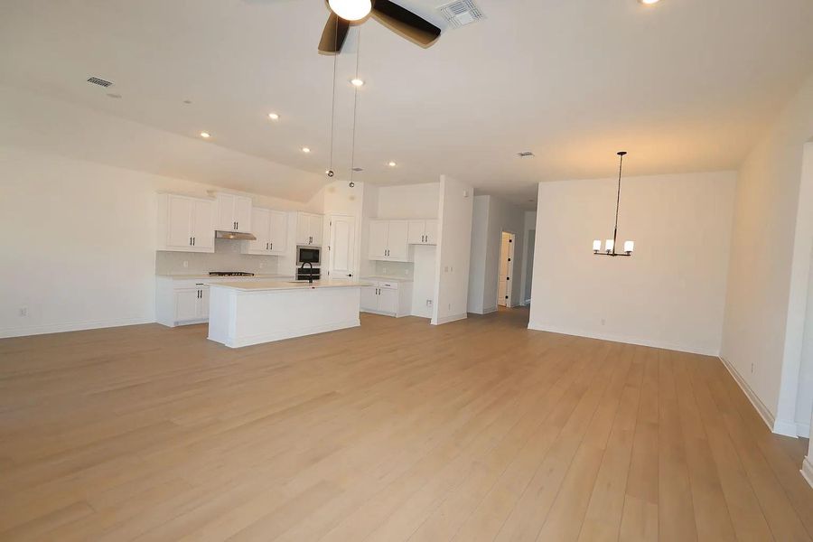Spacious open-concept living area featuring light-toned flooring, white walls, and recessed lighting