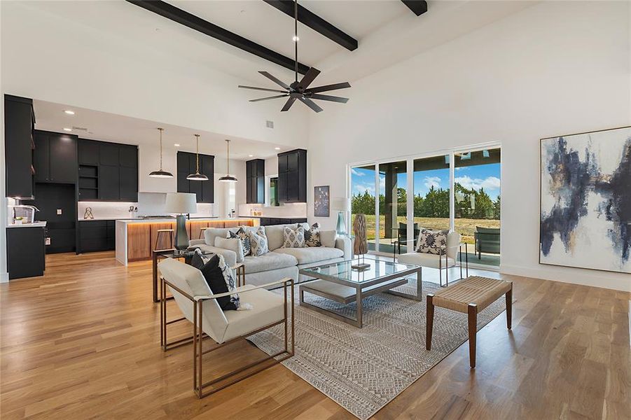 Living room with ceiling fan, light wood-type flooring, beam ceiling, and high vaulted ceiling