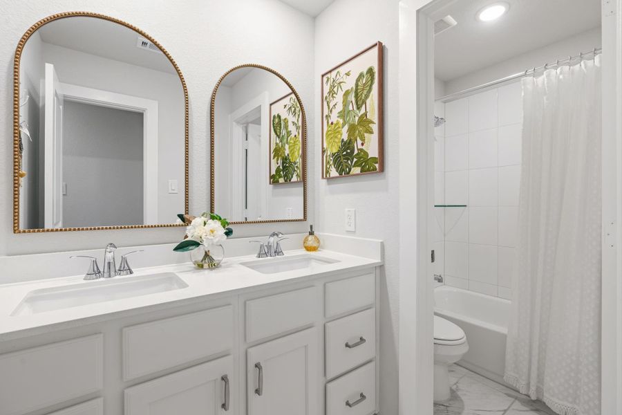 Secondary bathroom with double sinks, updated mirrors, cabinet hardware, and separate tub/shower and toilet area with door.