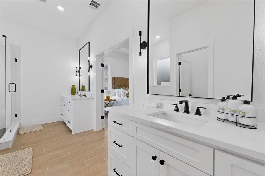 Bathroom with two vanities, wood tiled floors, a shower stall, ensuite bathroom, and recessed lighting