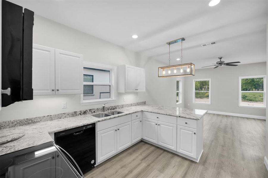 Kitchen with ceiling fan, white cabinets, visible vents, black dishwasher, and a sink Kitchen with ceiling fan, white cabinets, visible vents, black dishwasher, and a sink