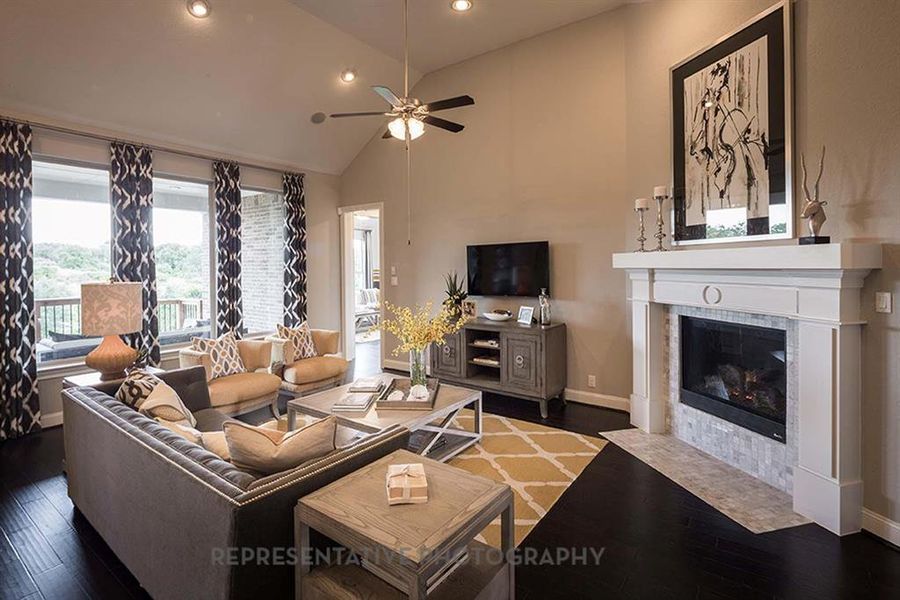 Living area featuring dark wood-style flooring, a fireplace, recessed lighting, high vaulted ceiling, and a ceiling fan Living area featuring dark wood-style flooring, a fireplace, recessed lighting, high vaulted ceiling, and a ceiling fan