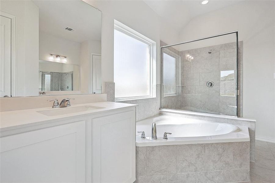 Bathroom featuring vanity, lofted ceiling, independent shower and bath, and tile patterned flooring