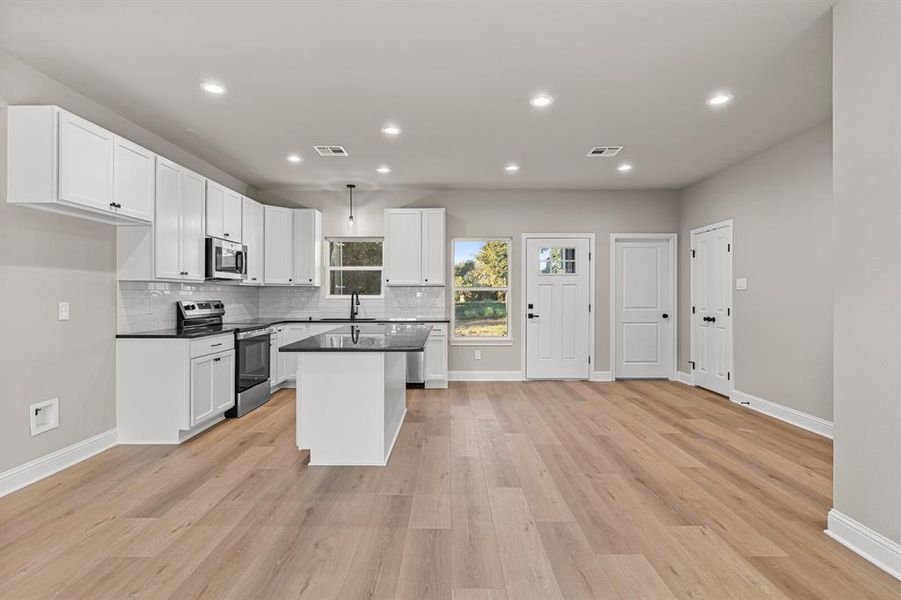 Kitchen featuring stainless steel appliances, backsplash, white cabinets, a center island, and recessed lighting Kitchen featuring stainless steel appliances, backsplash, white cabinets, a center island, and recessed lighting