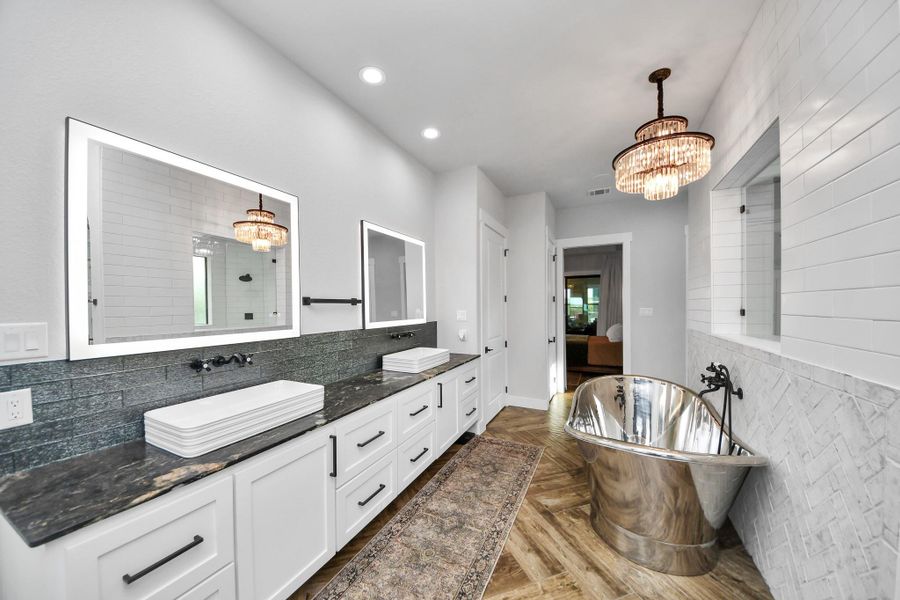 Luxurious bathroom featuring a stunning freestanding metallic tub, dual sinks with elegant countertops, and chic modern lighting.