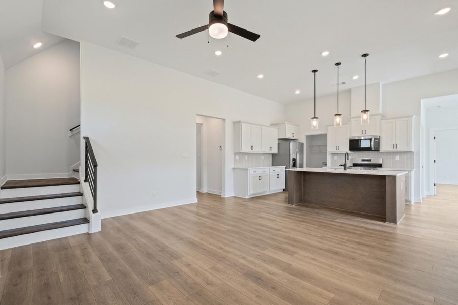 Open-concept living area with wood-finish flooring, recessed lighting, and a ceiling fan Open-concept living area with wood-finish flooring, recessed lighting, and a ceiling fan