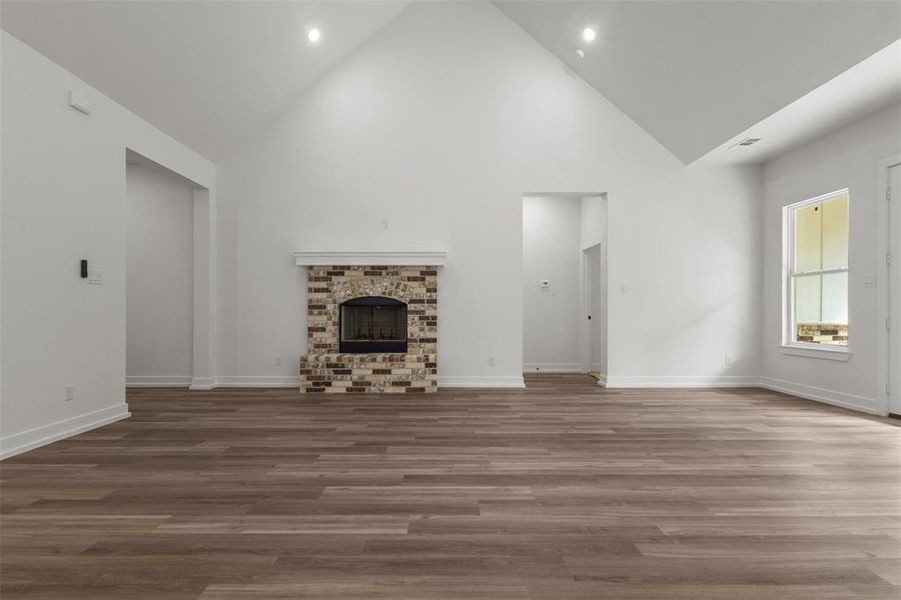 Spacious living area featuring high vaulted ceilings, light-colored walls, and wood-style flooring