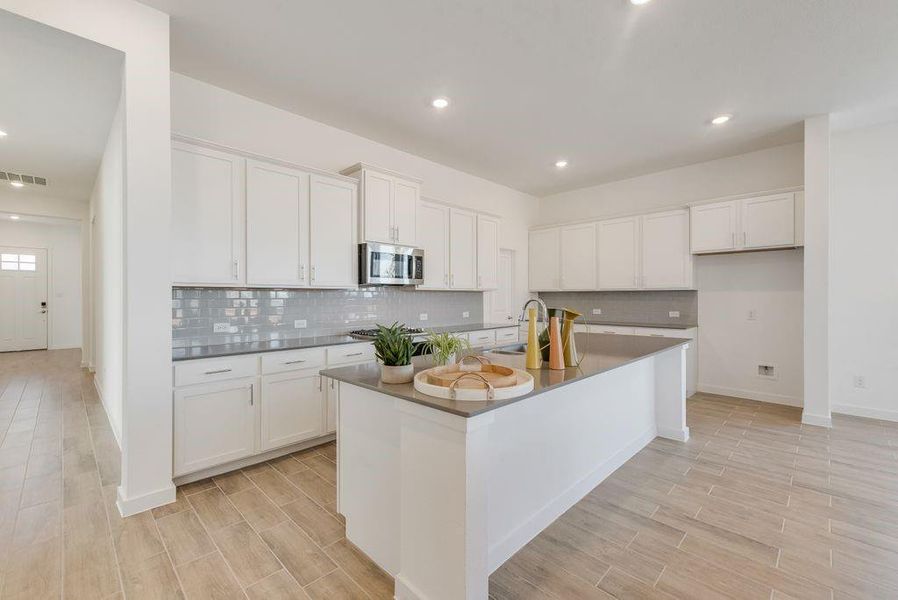 Kitchen with appliances with stainless steel finishes, dark countertops, light wood-style floors, tasteful backsplash, and recessed lighting