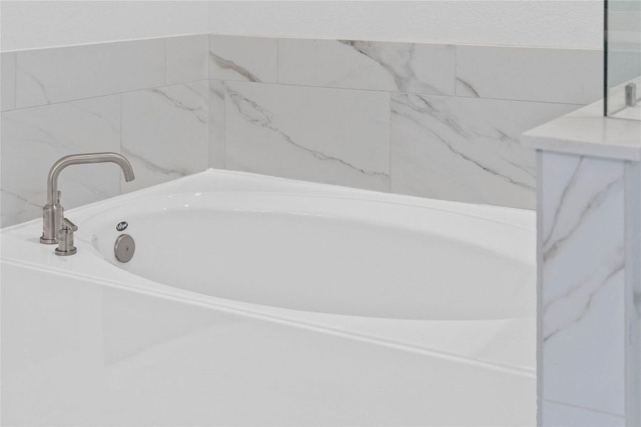 Unwind after a long day in the deep, corner soaking tub, a perfect sanctuary for relaxation. The tub is accented by stylish, warm-toned fixtures.