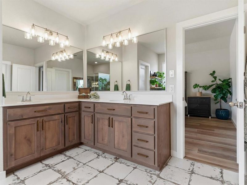 Primary bathroom featuring dual vanities, soaking tub, and separate shower.