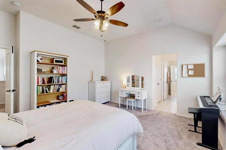 Bedroom with connected bathroom, light carpet, a ceiling fan, and lofted ceiling