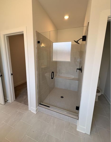 Glass-enclosed shower with matte black fixtures, integrated bench, and frosted window Glass-enclosed shower with matte black fixtures, integrated bench, and frosted window