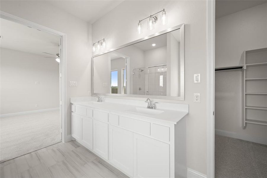 Bathroom featuring ceiling fan, a shower stall, double vanity, and a spacious closet