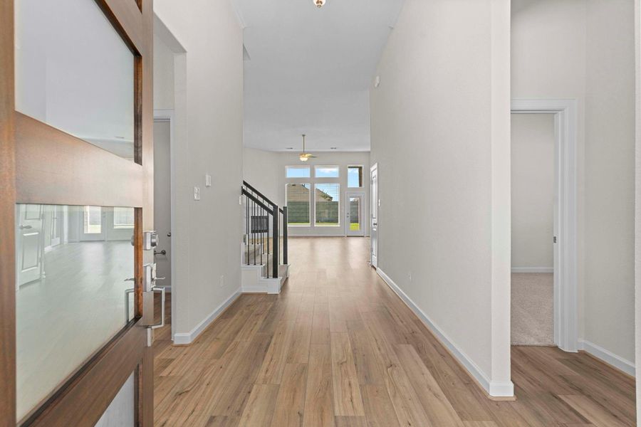 Welcoming covered entry with stone columns and elegant glass-panel front door, setting the stage for the stylish interiors.