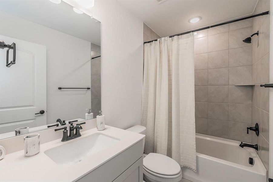 Full bathroom featuring vanity, toilet, and shower / bathtub combination with curtain