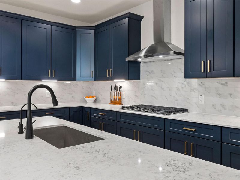 Kitchen featuring blue cabinets, light stone counters, and decorative backsplash