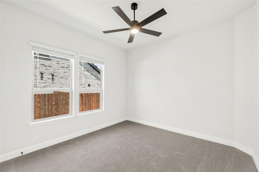 Empty bedroom with gray carpet, white walls, ceiling fan, and double windows Empty bedroom with gray carpet, white walls, ceiling fan, and double windows