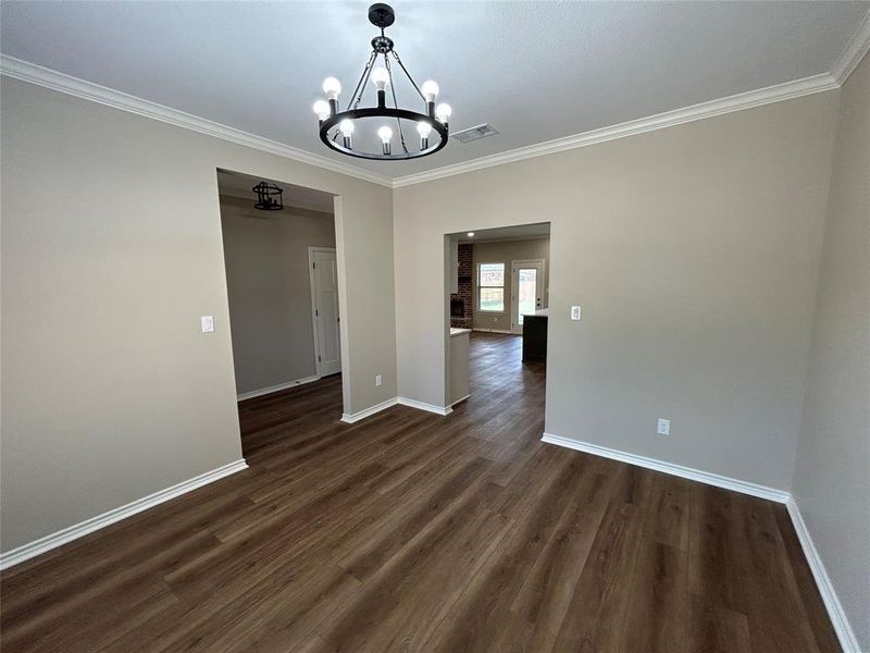 Unfurnished dining area with crown molding, dark wood-style flooring, and a chandelier