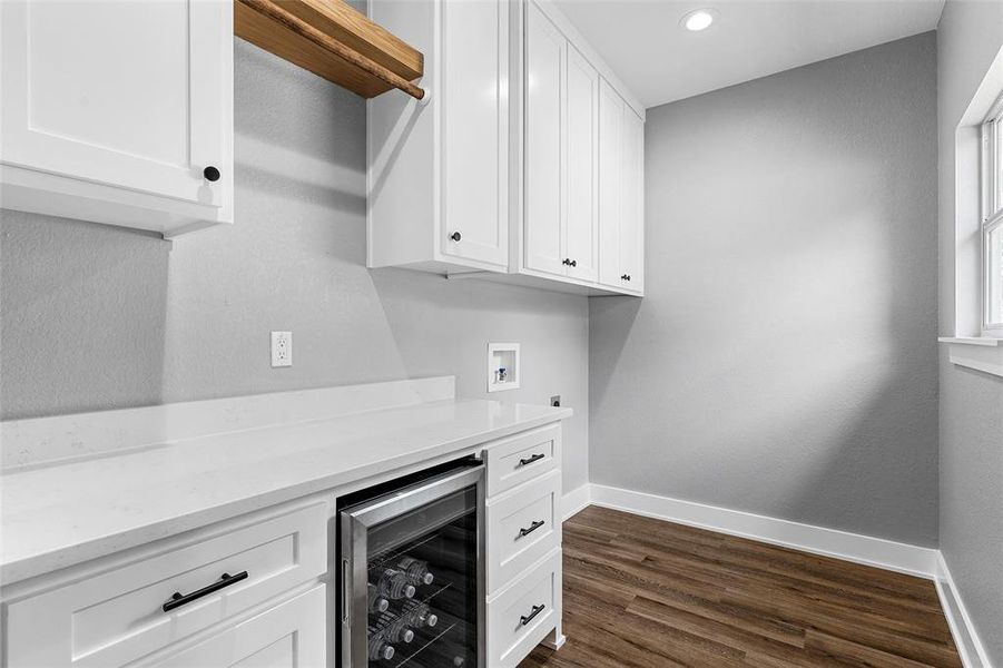 Laundry area featuring wine cooler, hookup for a washing machine, cabinet space, dark wood-style flooring, and recessed lighting