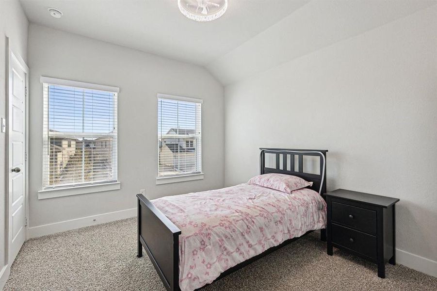 Bedroom featuring light colored carpet, fandalier, natural light, and vaulted ceiling