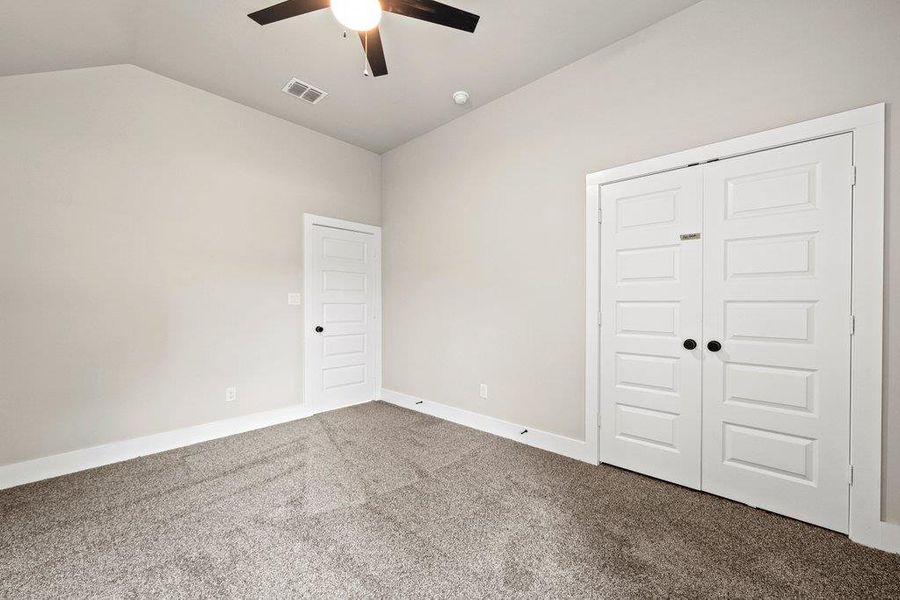 Unfurnished bedroom with carpet flooring, vaulted ceiling, a closet, a ceiling fan, and baseboards Unfurnished bedroom with carpet flooring, vaulted ceiling, a closet, a ceiling fan, and baseboards