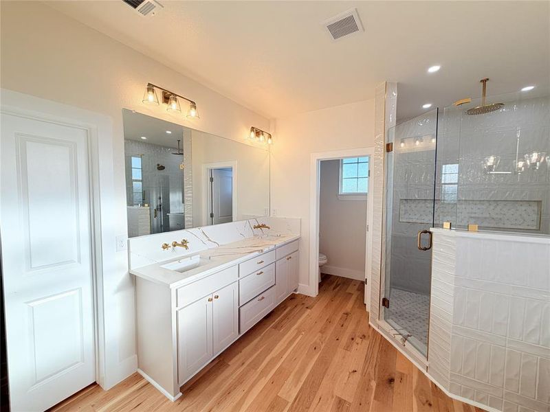 Bathroom featuring double vanity, a shower stall, light wood-style floors, and recessed lighting Bathroom featuring double vanity, a shower stall, light wood-style floors, and recessed lighting