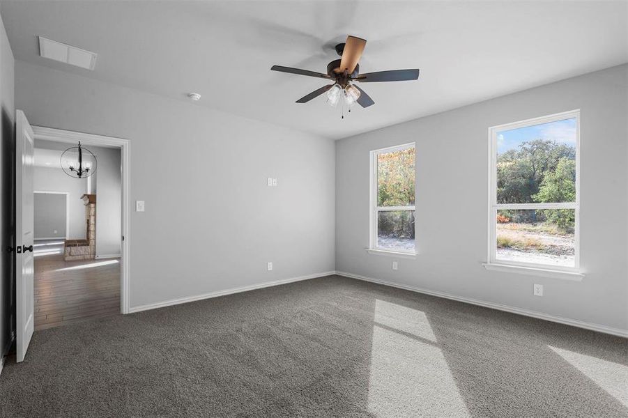 Spare room featuring ceiling fan with notable chandelier and dark hardwood / wood-style flooring