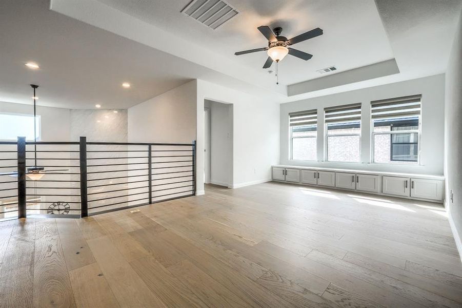 Unfurnished room featuring hardwood / wood-style floors, a tray ceiling, and visible vents