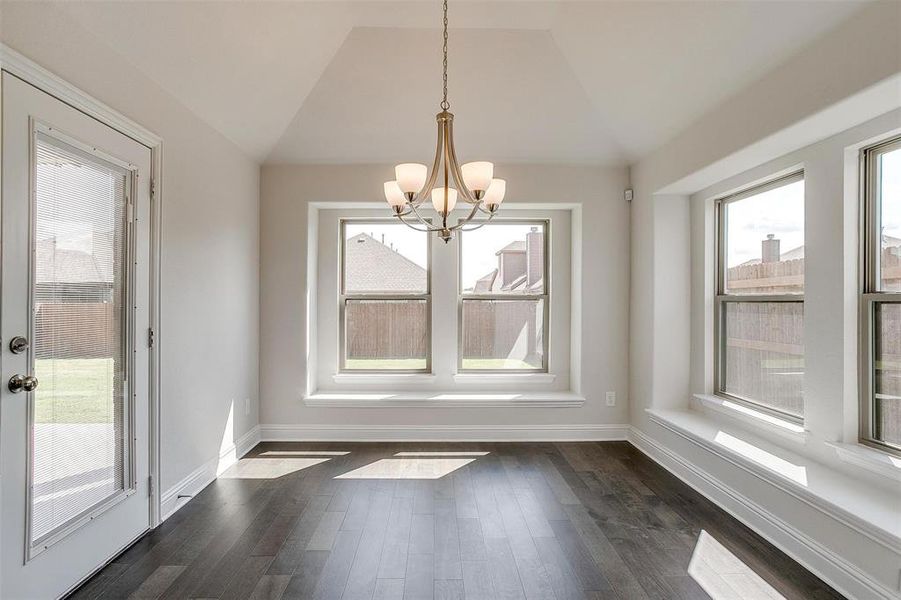 Unfurnished dining area with a notable chandelier, vaulted ceiling, and dark wood-type flooring