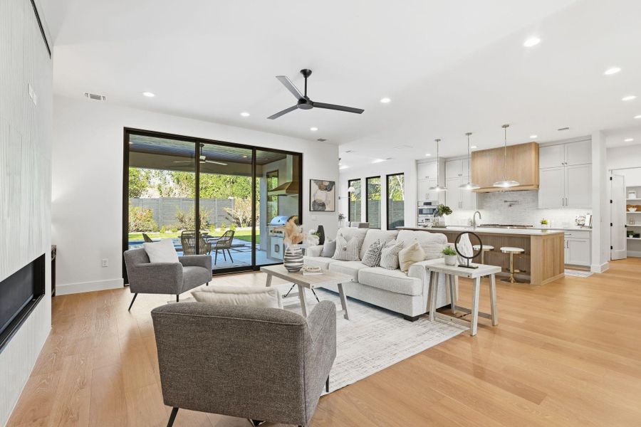 Living area featuring a fireplace, light wood-type flooring, ceiling fan, and recessed lighting Living area featuring a fireplace, light wood-type flooring, ceiling fan, and recessed lighting