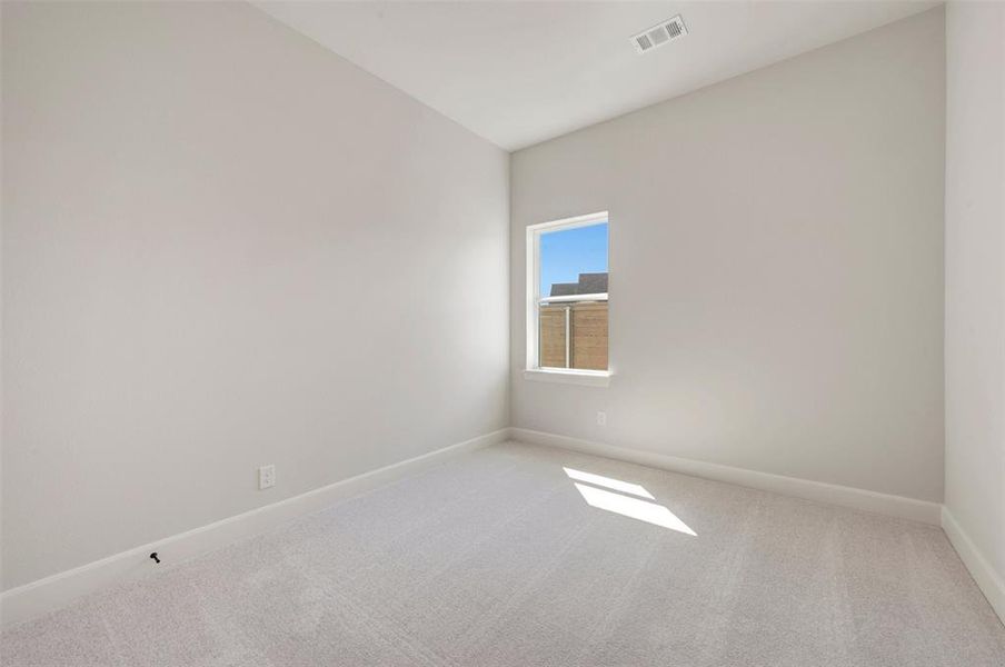 Spacious room featuring neutral carpeting, light-toned walls, and a single window providing natural illumination