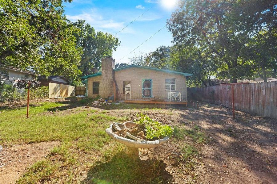 Rear view of property with a fenced backyard, a chimney, a wooden deck, and brick siding