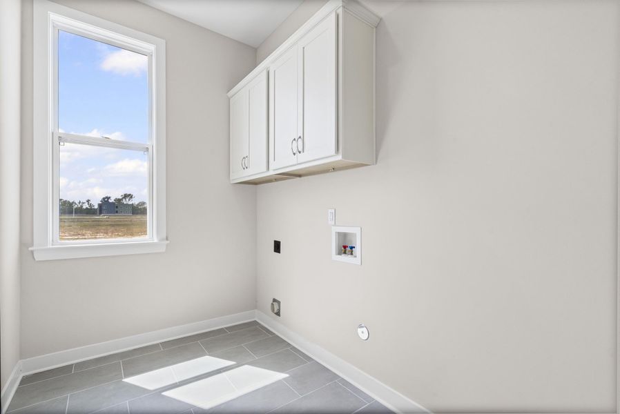 Washroom featuring hookup for a washing machine, light tile patterned floors, cabinet space, and hookup for an electric dryer