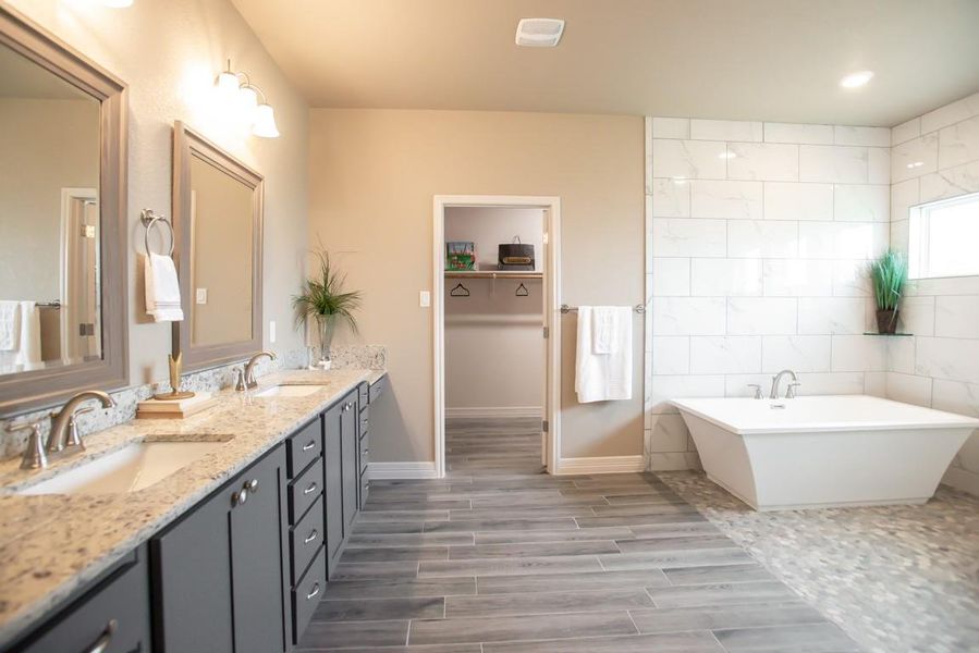 Bathroom with double vanity, a soaking tub, wood finished floors, and tile walls Bathroom with double vanity, a soaking tub, wood finished floors, and tile walls