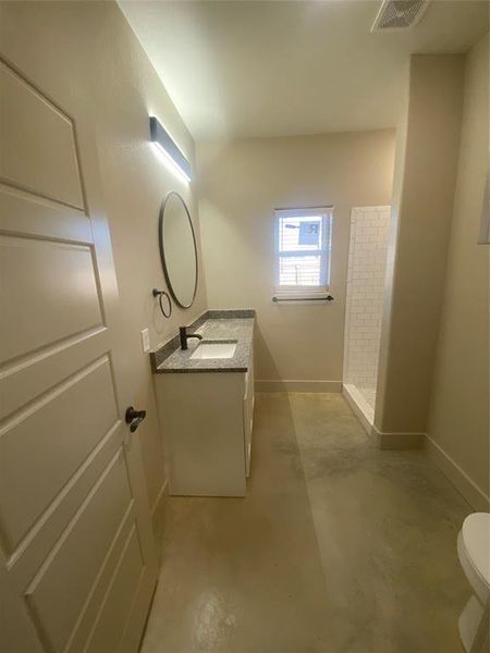 Bathroom featuring vanity, concrete floors, toilet, and walk in shower