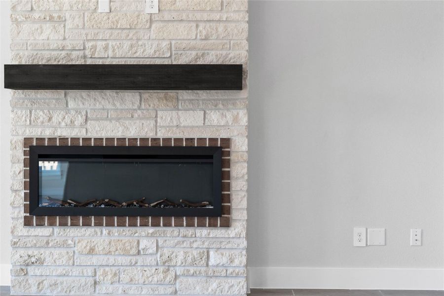The sleek linear gas insert is framed by a decorative brick border, creating a unique architectural detail. The look is completed with a dark espresso wood-beam mantel, providing a bold contrast against the natural white stone. The sleek linear gas insert is framed by a decorative brick border, creating a unique architectural detail. The look is completed with a dark espresso wood-beam mantel, providing a bold contrast against the natural white stone.
