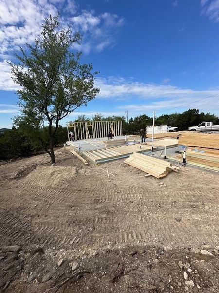 A new construction is underway, featuring a partial wood frame structure, lumber materials, and a clear blue sky
