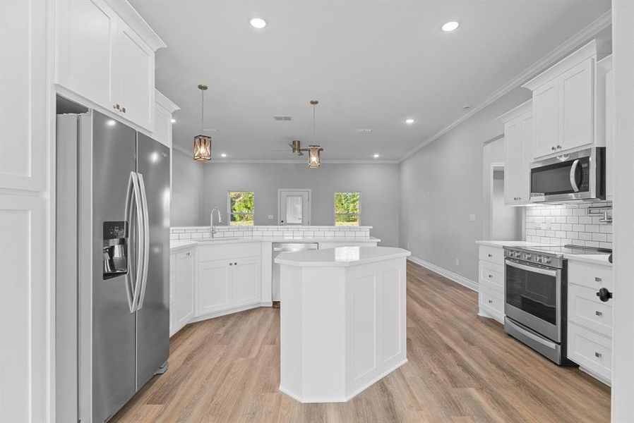 Kitchen with a peninsula, stainless steel appliances, decorative backsplash, recessed lighting, and white cabinetry
