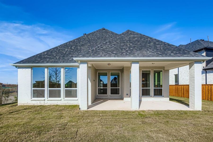 Rear view of property featuring brick siding, a shingled roof, and a patio area