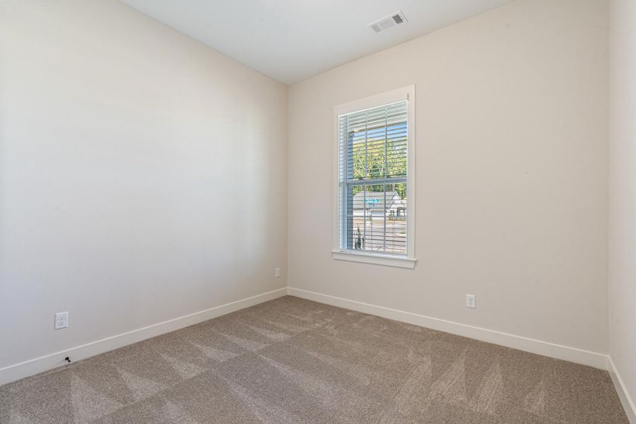 Neutral-toned walls, patterned carpet, and a window with blinds Neutral-toned walls, patterned carpet, and a window with blinds