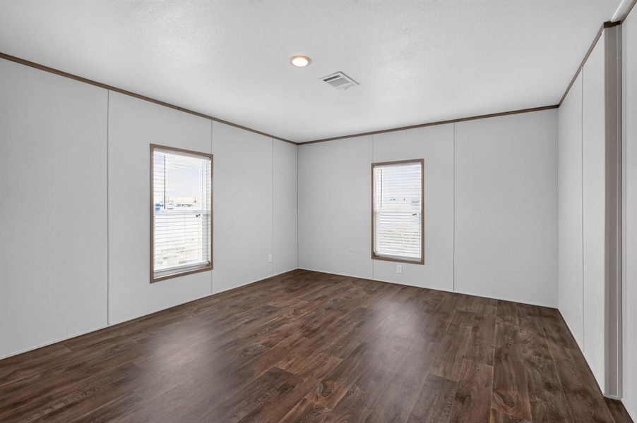 A spacious room offers durable wood flooring and ample natural light from multiple windows.