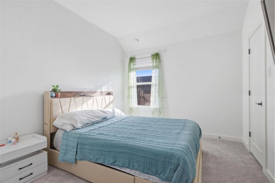 A well-lit room with soft carpet flooring and a sun-filled window offering comfort.
