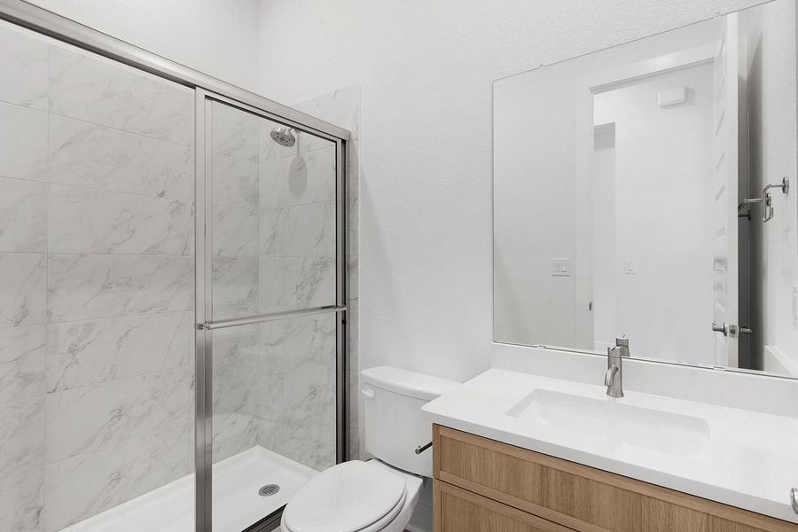 A modern bathroom features a sleek vanity with ample storage and a glass-enclosed shower.