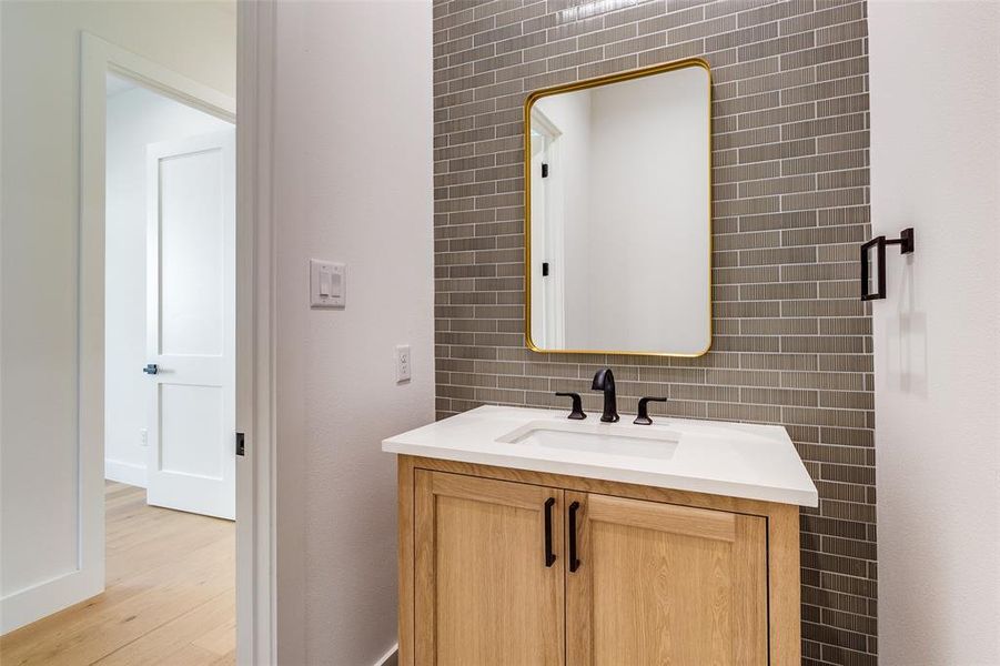 Bathroom featuring vanity, tile walls, wood-type flooring, and decorative backsplash